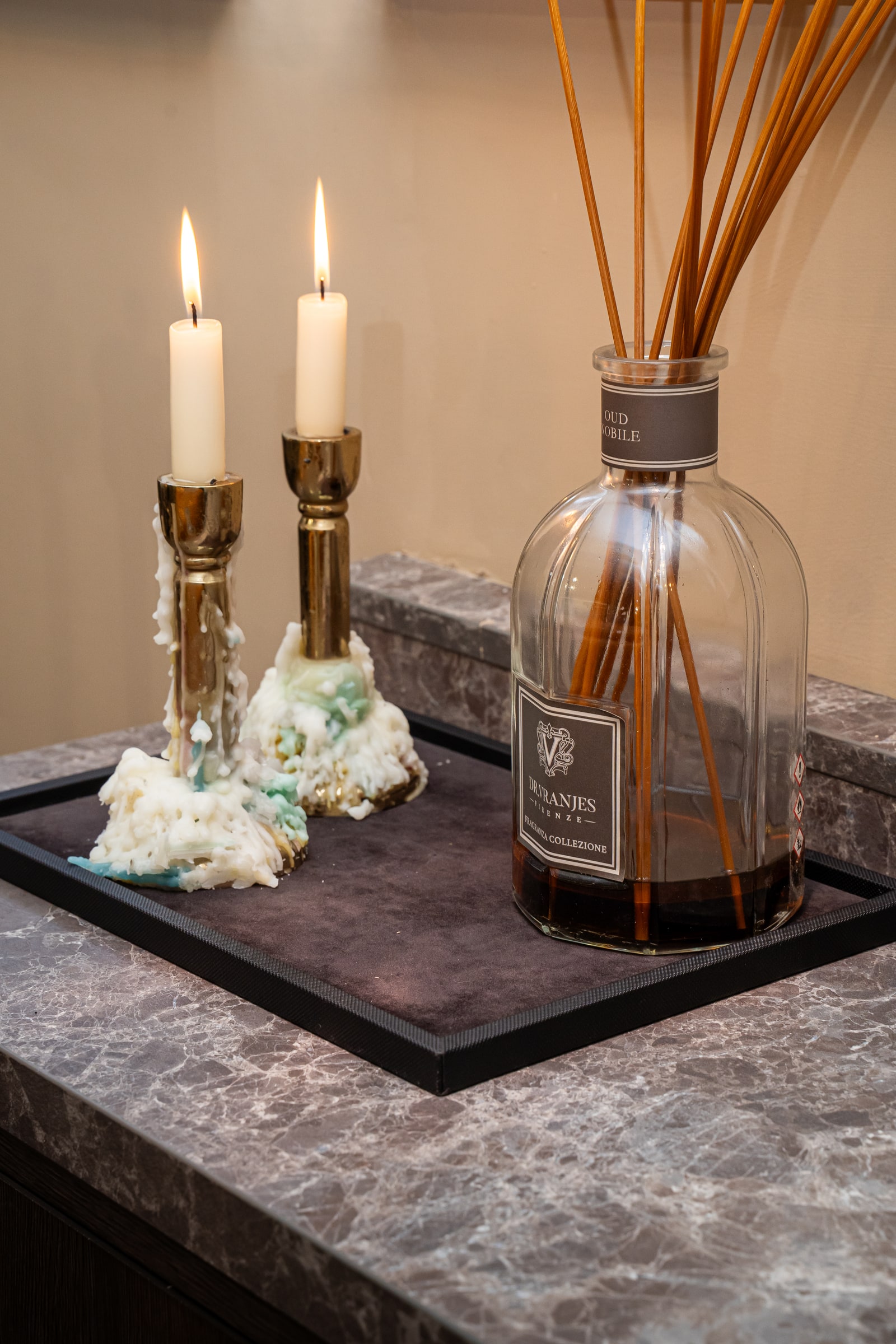 Candles and a reed diffuser on a marble surface at ASK
