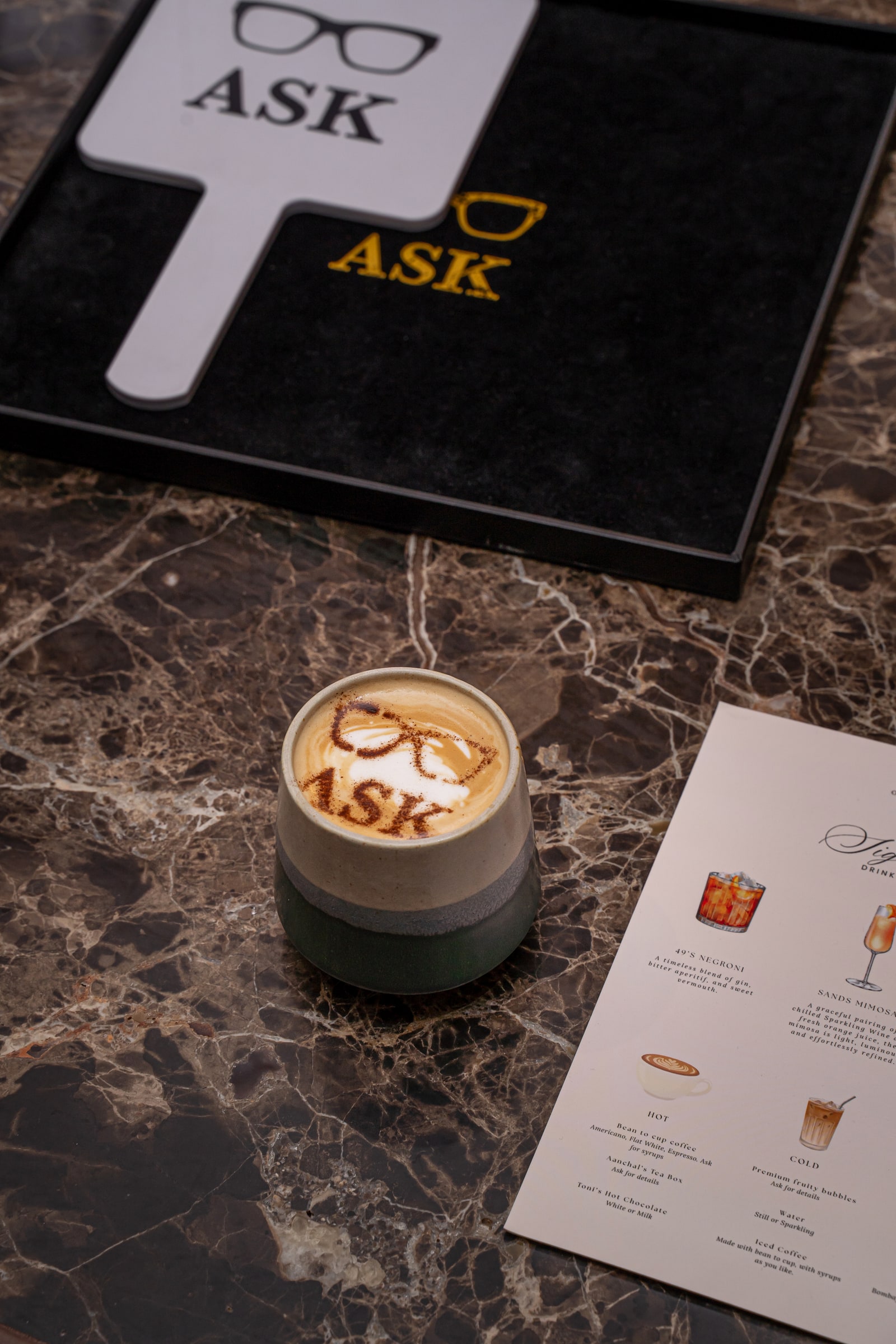 An ASK coffee beside the hand mirror, presentation tray and drinks menu
