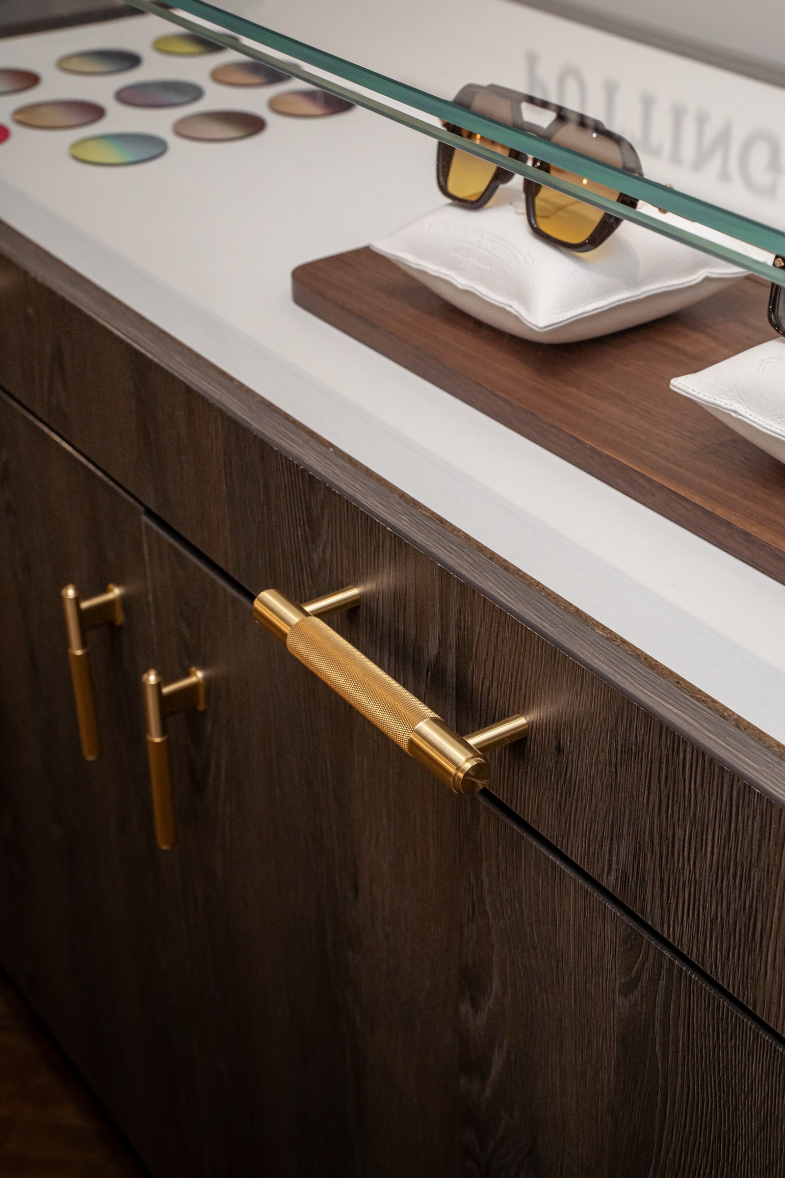 Eyewear displayed on white cushions inside the glass-topped cabinet
