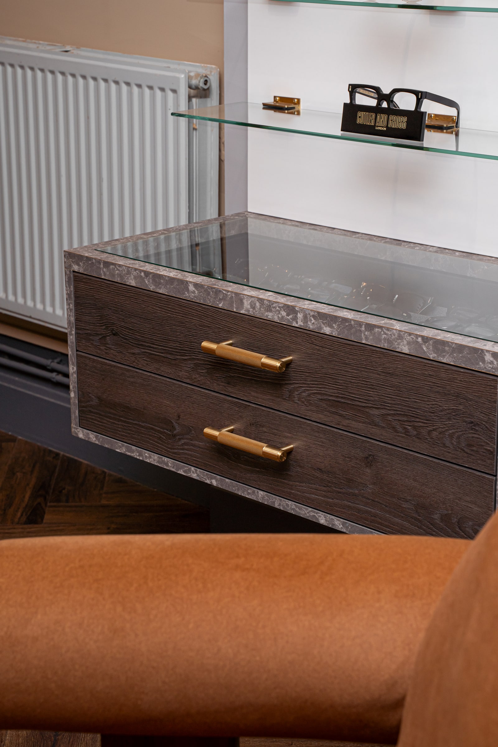 Dark wood frame drawers with brass handles beneath the glass display shelves