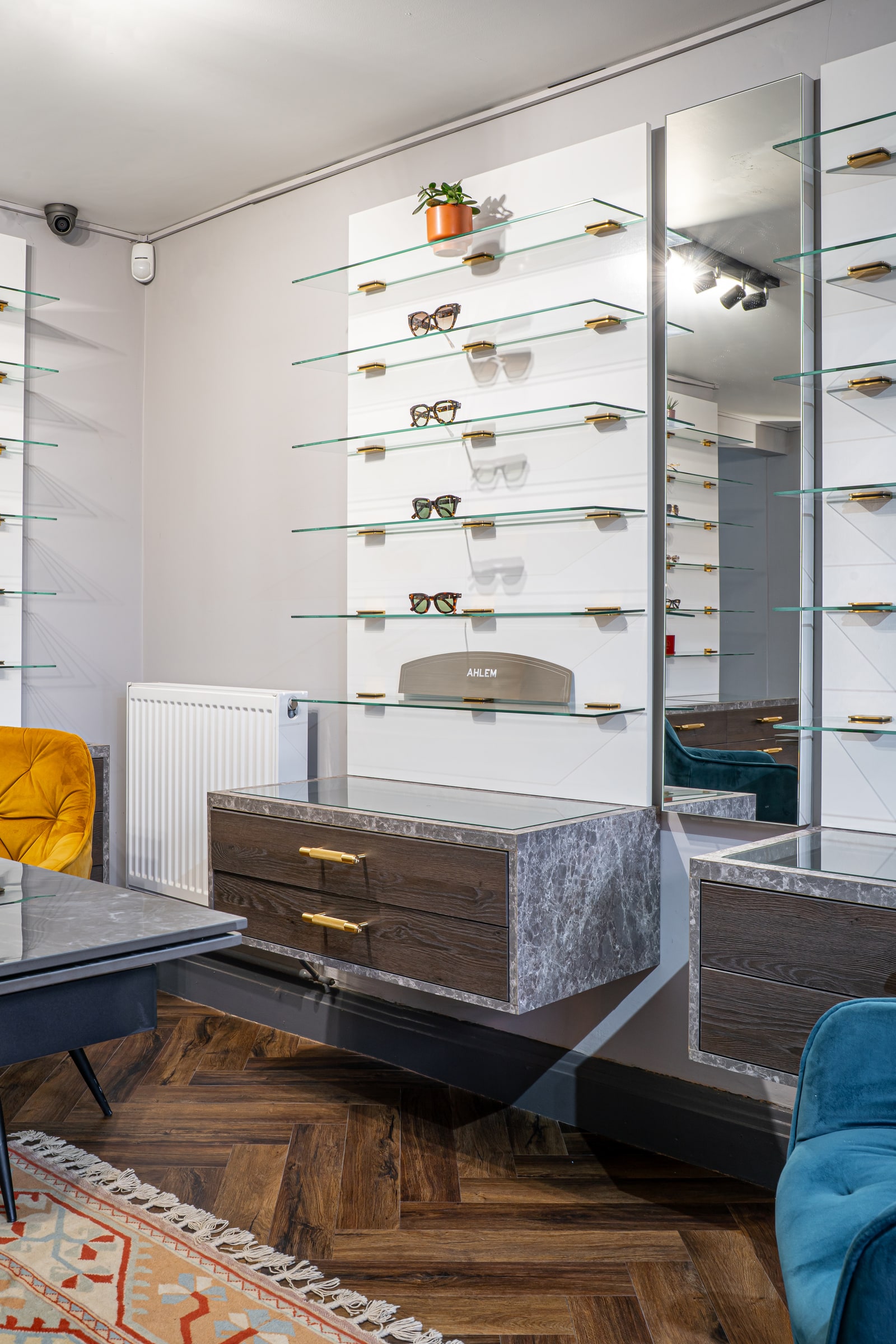 Eyewear displayed on illuminated glass shelves above marble-topped drawers