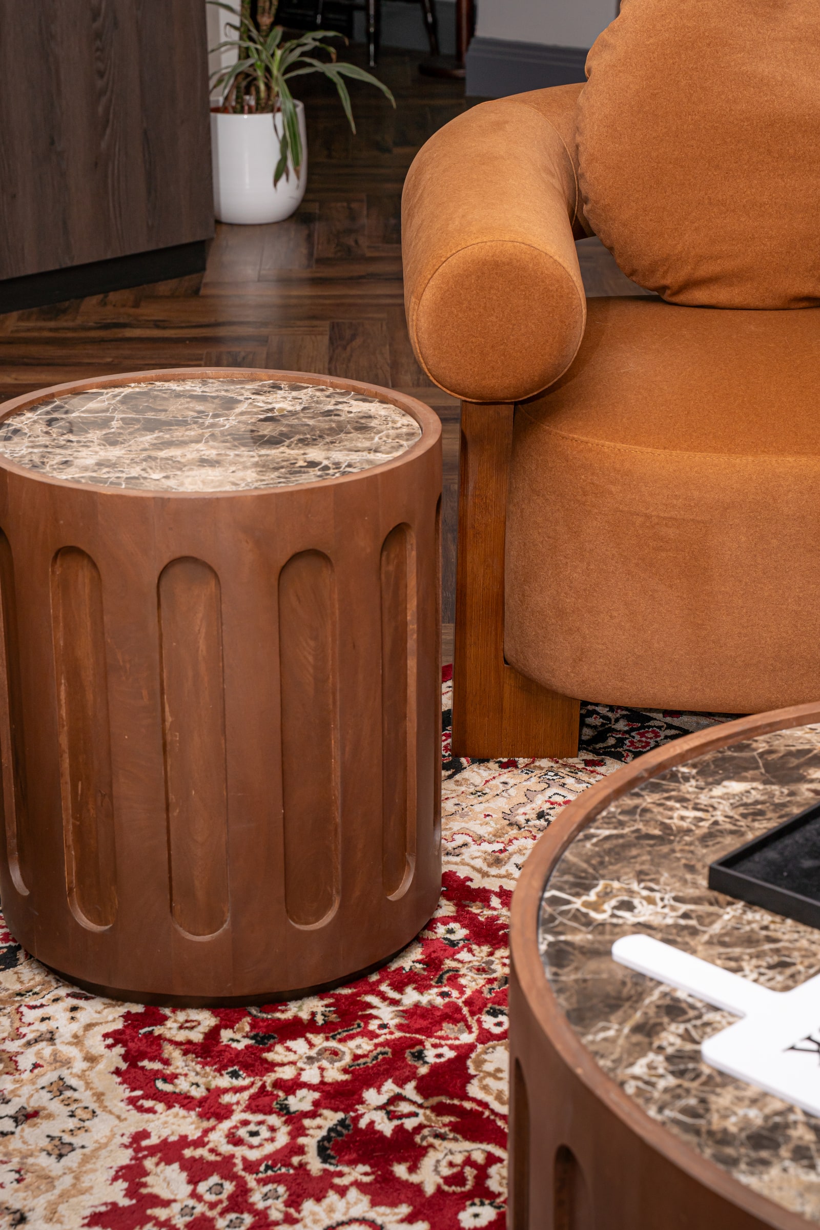 A brown lounge chair and marble-topped side table beside the rug