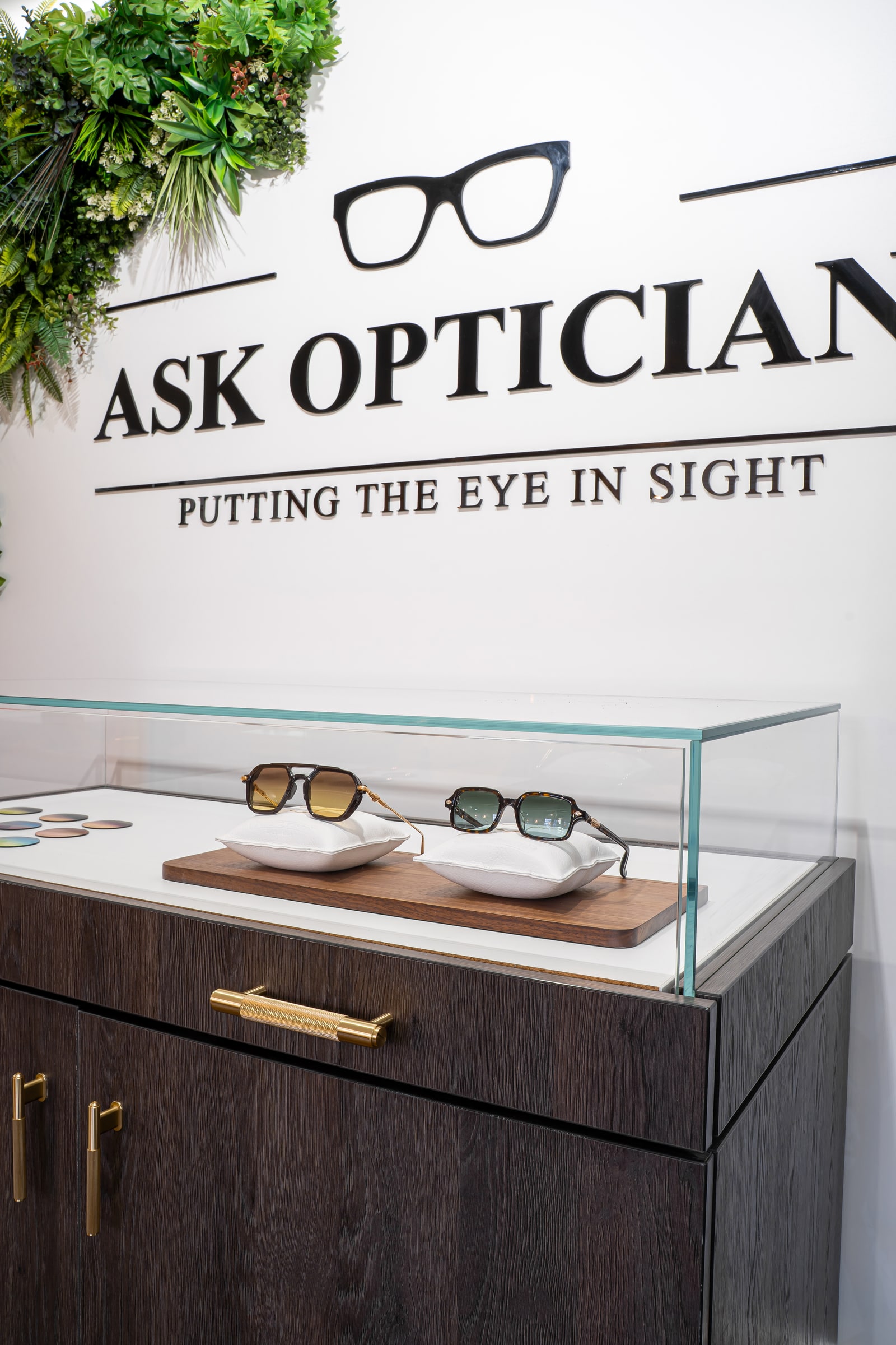 The ASK Opticians wall sign above the glass eyewear display