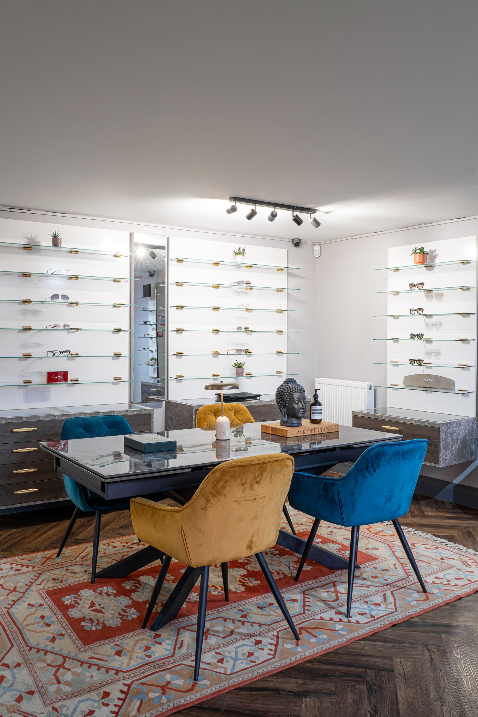 The eyewear styling table with blue and gold chairs surrounded by frame displays